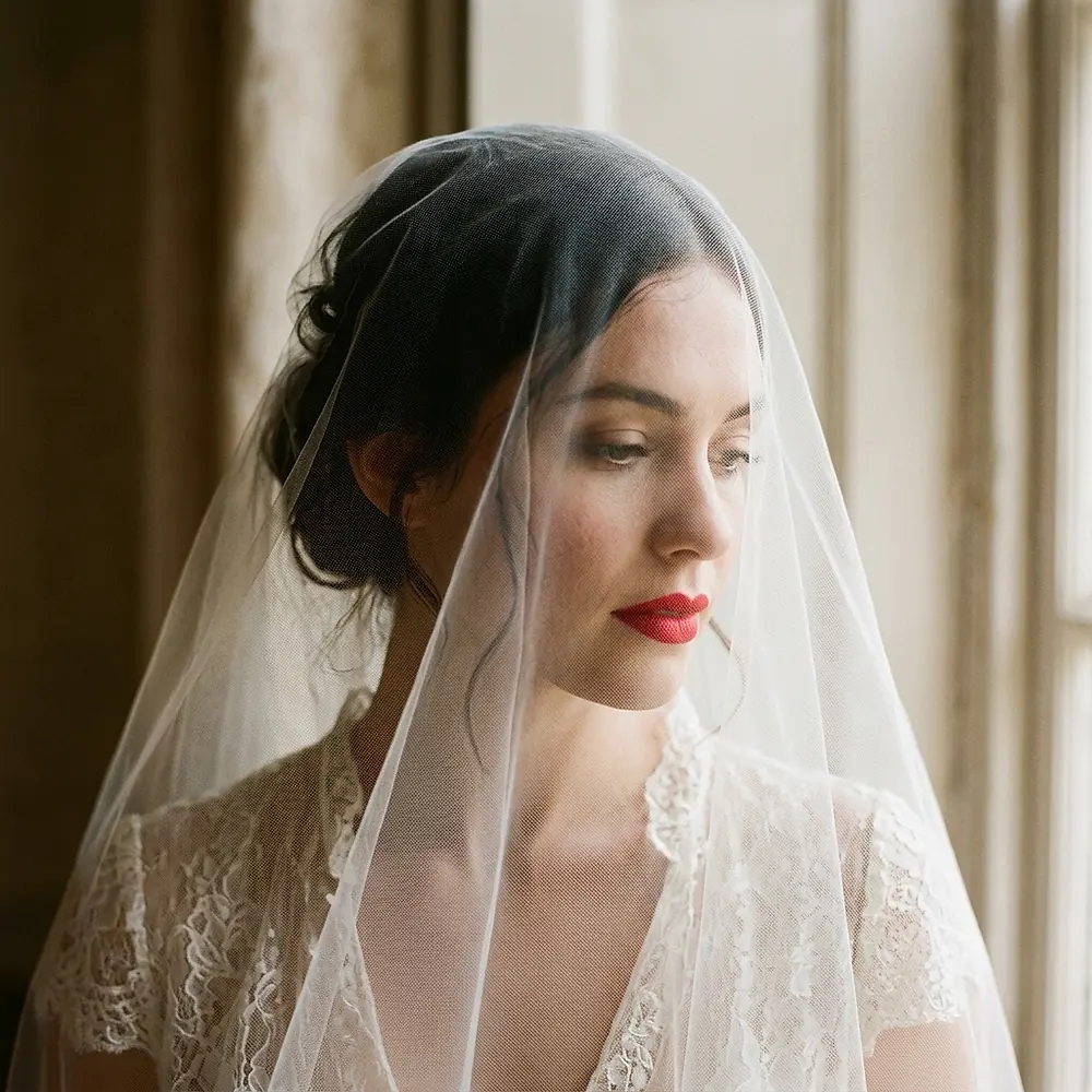 A close editorial portrait of a bride in a sheer veil.