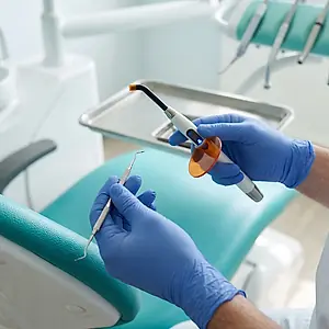 A dentist holding a filling instrument and a curing light.