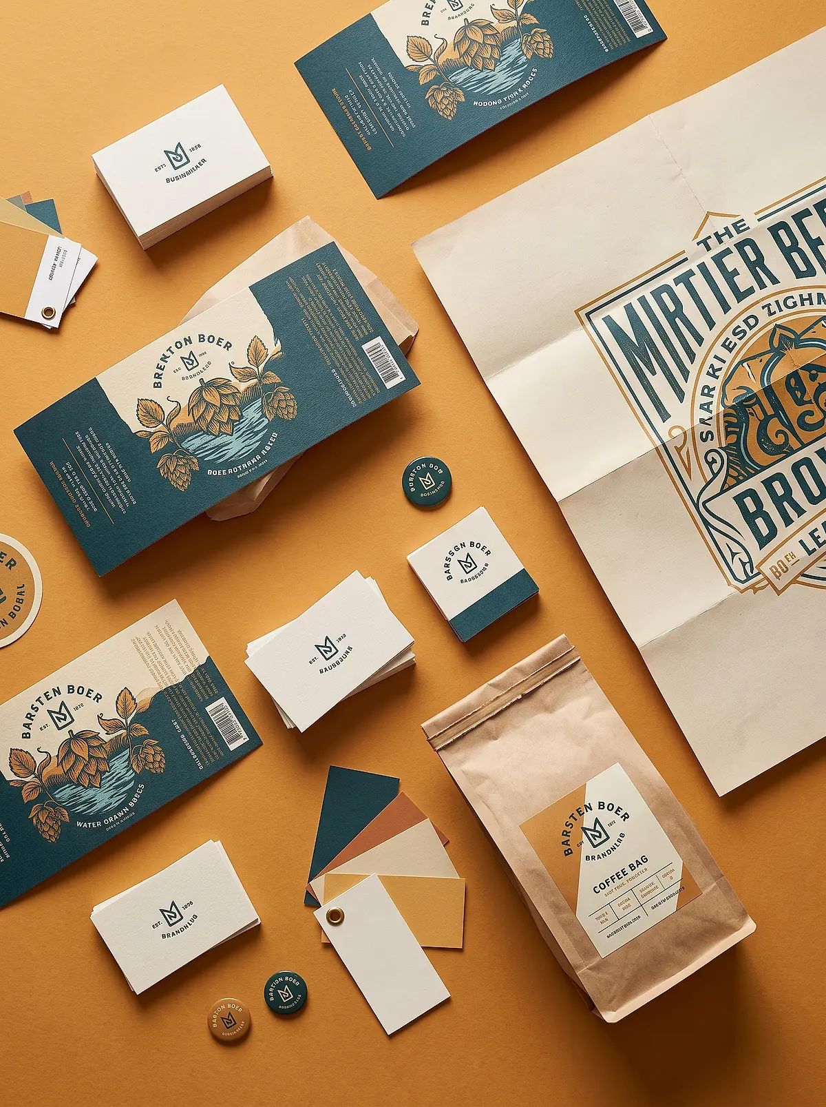 Labels, business cards, a folded poster and swatch cards laid out on an amber background