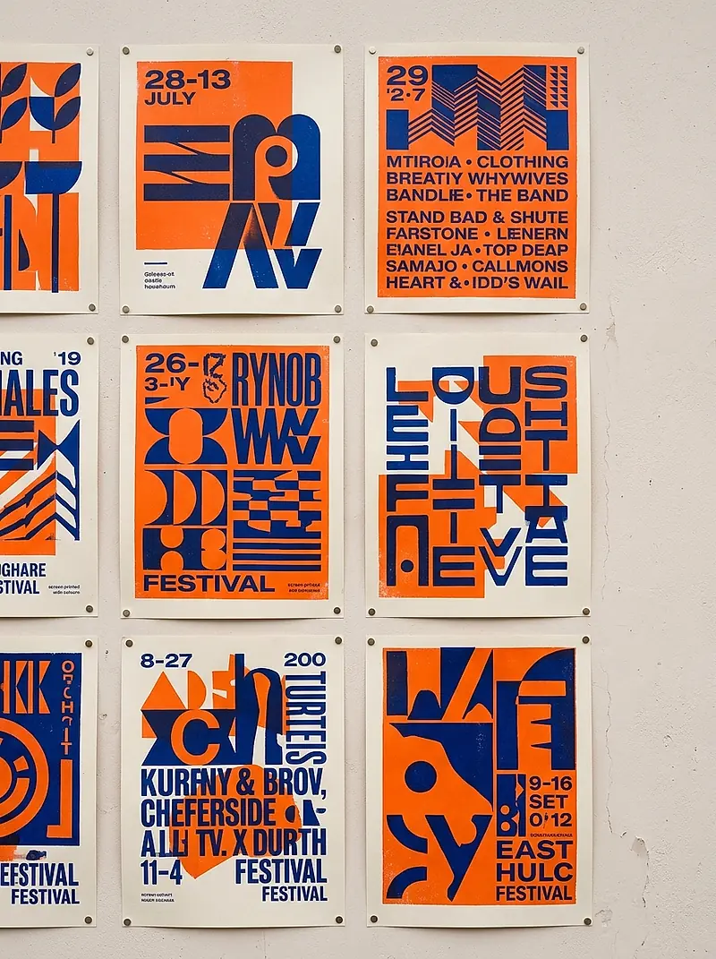 Screen-printed festival posters pinned in a grid on a pale wall