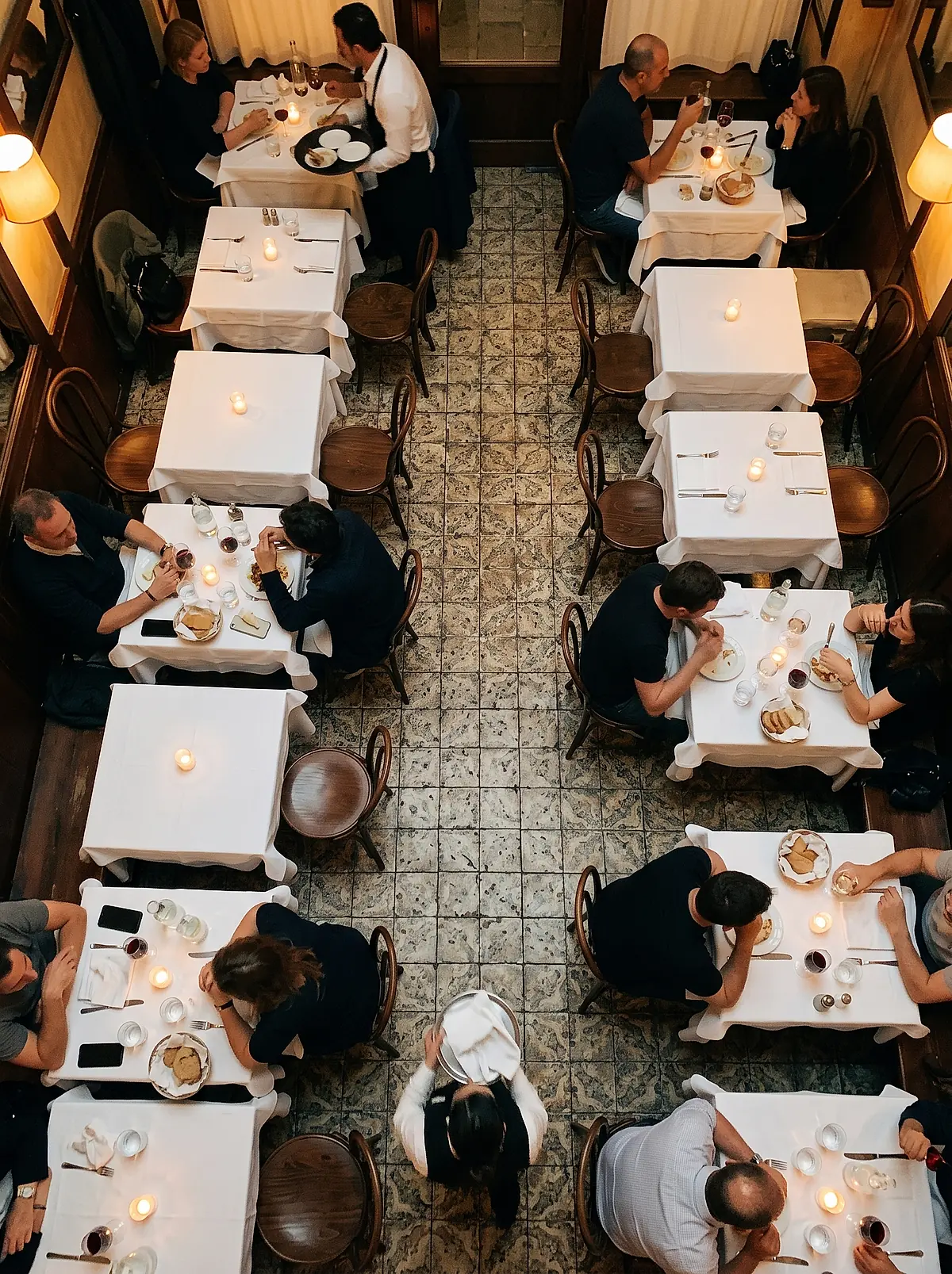 Diners at candlelit tables in the trattoria dining room, seen from above