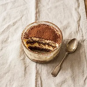 Tiramisu dusted with cocoa, served in a glass dish