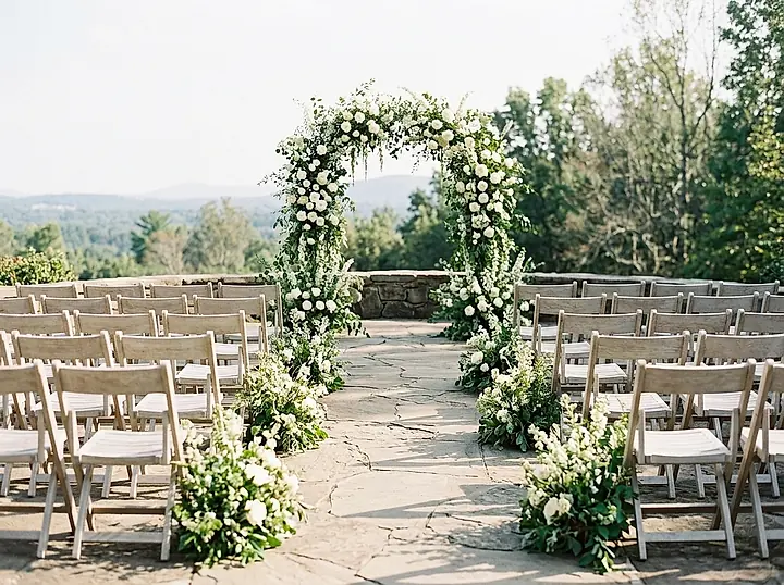 Rows of chairs and a white floral arch at an outdoor wedding ceremony