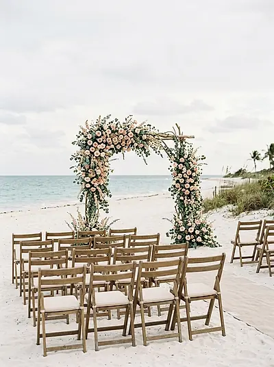 A ceremony arch on white sand with the sea behind