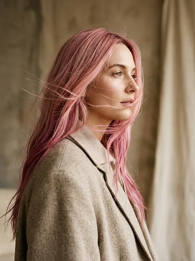 A woman with long rose-pink hair, turning her head as it moves.