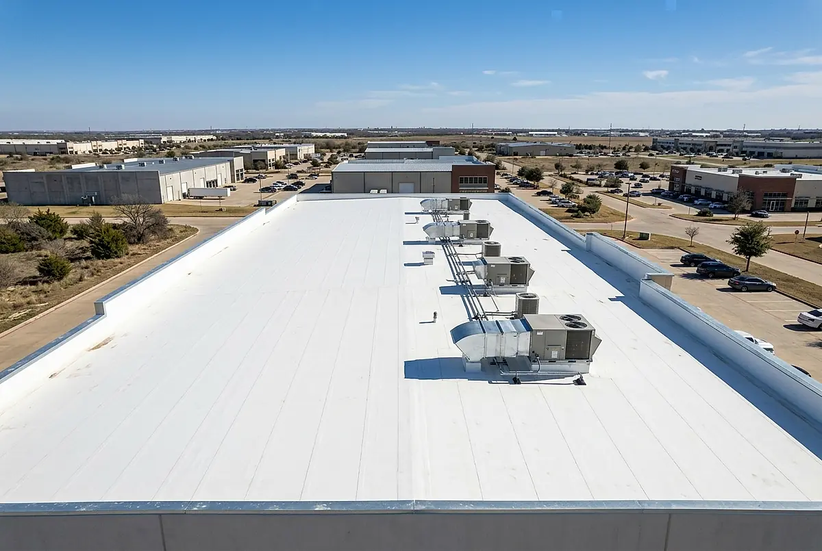 A white TPO membrane roof on a commercial building, with rooftop units and new edge flashing.