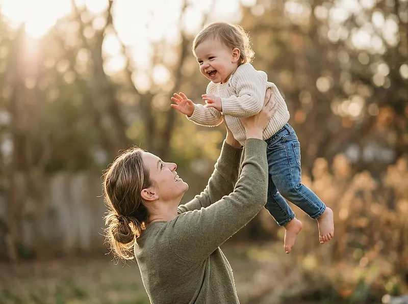 A parent lifting a laughing toddler.