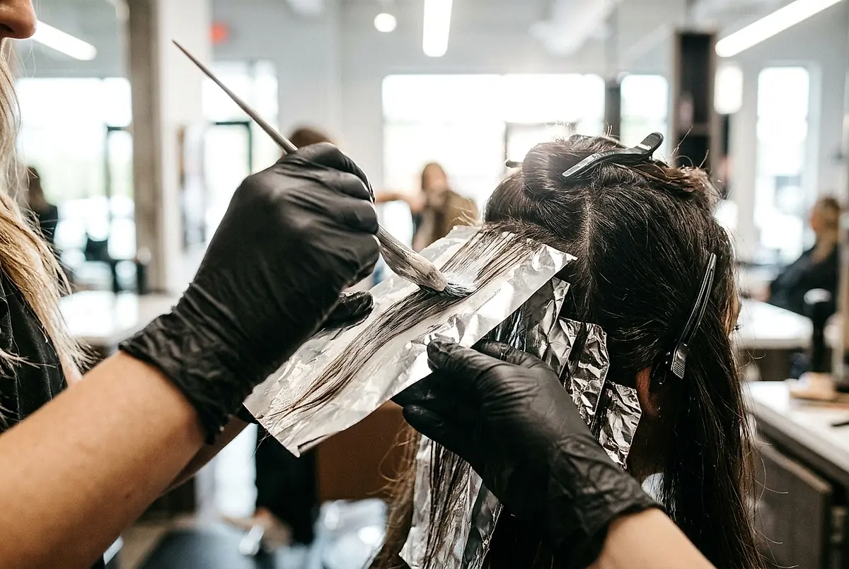 A stylist applying colour with a tint brush and fine foils