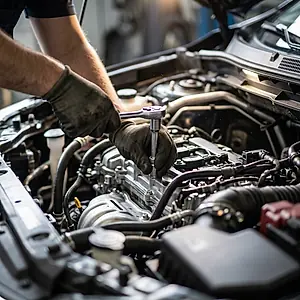 Gloved hands tightening a fitting in an engine bay with a socket wrench