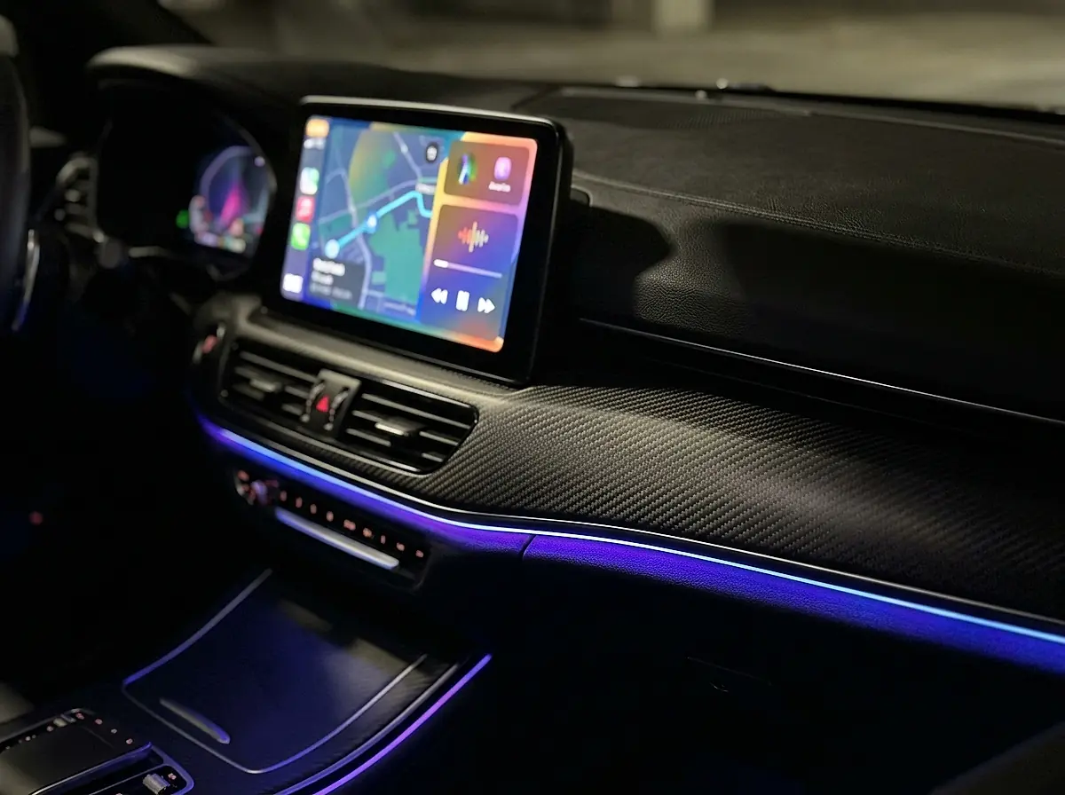 A car touchscreen display glowing in a dark dashboard