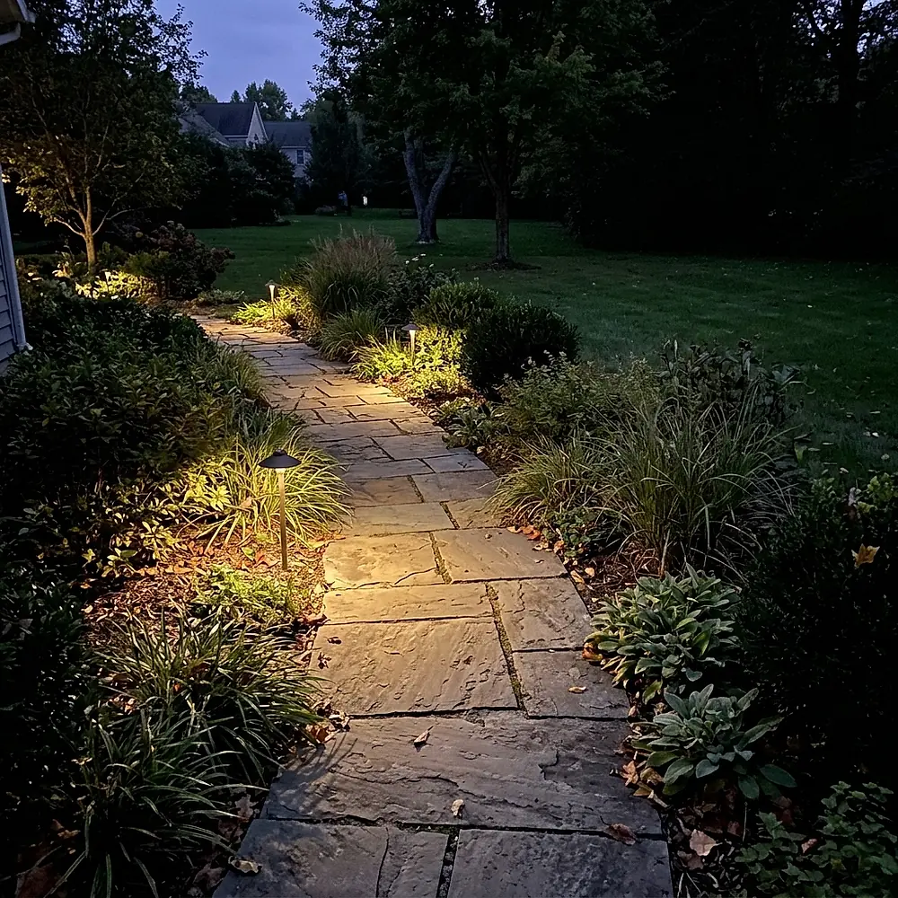 A stone walkway at dusk lit by small path lights